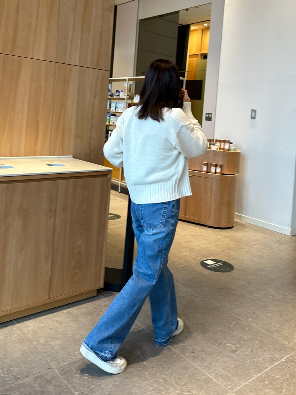 ホワイト系のカーディガン/ボレロ、ホワイト系のTシャツ/カットソー、ブルー系のデニムパンツを着用したレディースの春コーディネートの2枚目の写真