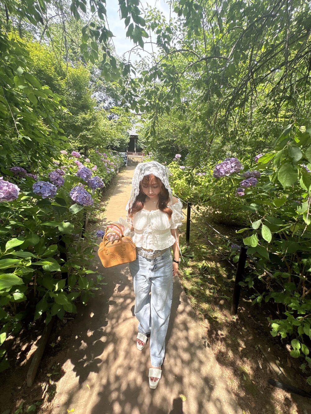 イエロー系のハンドバッグ、ホワイト系のシャツ/ブラウス、ブルー系のデニムパンツを着用したレディースの夏コーディネートの6枚目の写真