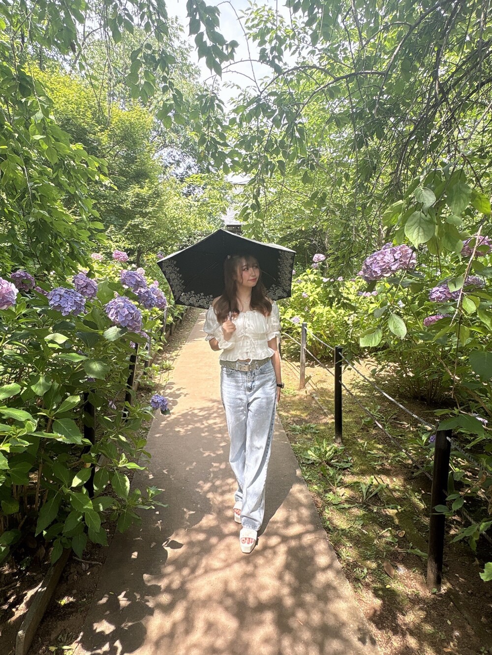 イエロー系のハンドバッグ、ホワイト系のシャツ/ブラウス、ブルー系のデニムパンツを着用したレディースの夏コーディネートの3枚目の写真