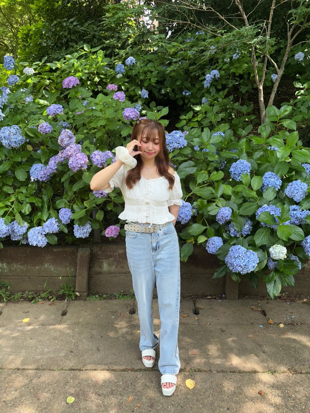 イエロー系のハンドバッグ、ホワイト系のシャツ/ブラウス、ブルー系のデニムパンツを着用したレディースの夏コーディネートの5枚目の写真