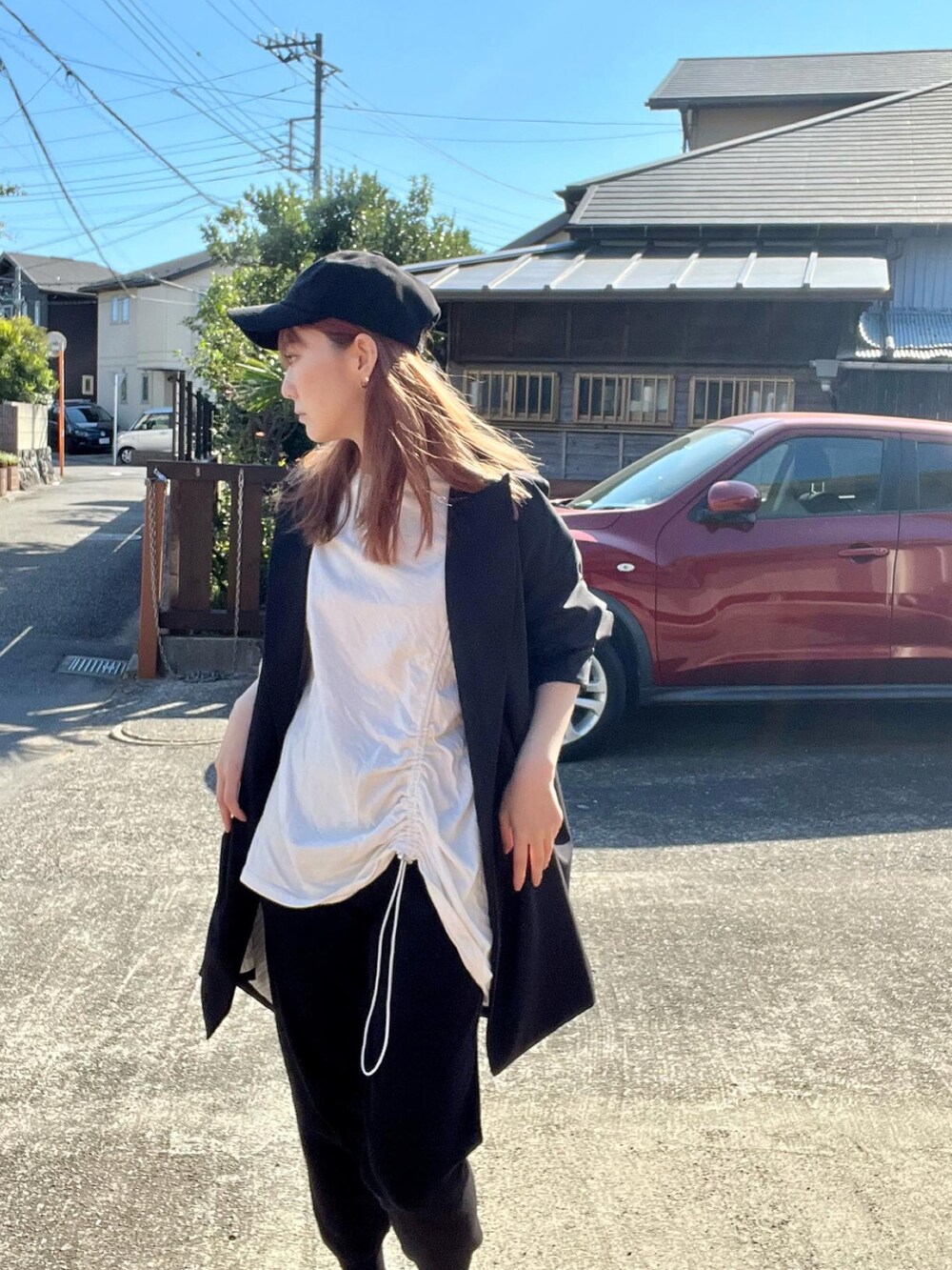 ブラック系のテーラードジャケット、ホワイト系のTシャツ/カットソー、ブラック系のパンツを着用したレディースの秋コーディネートの2枚目の写真