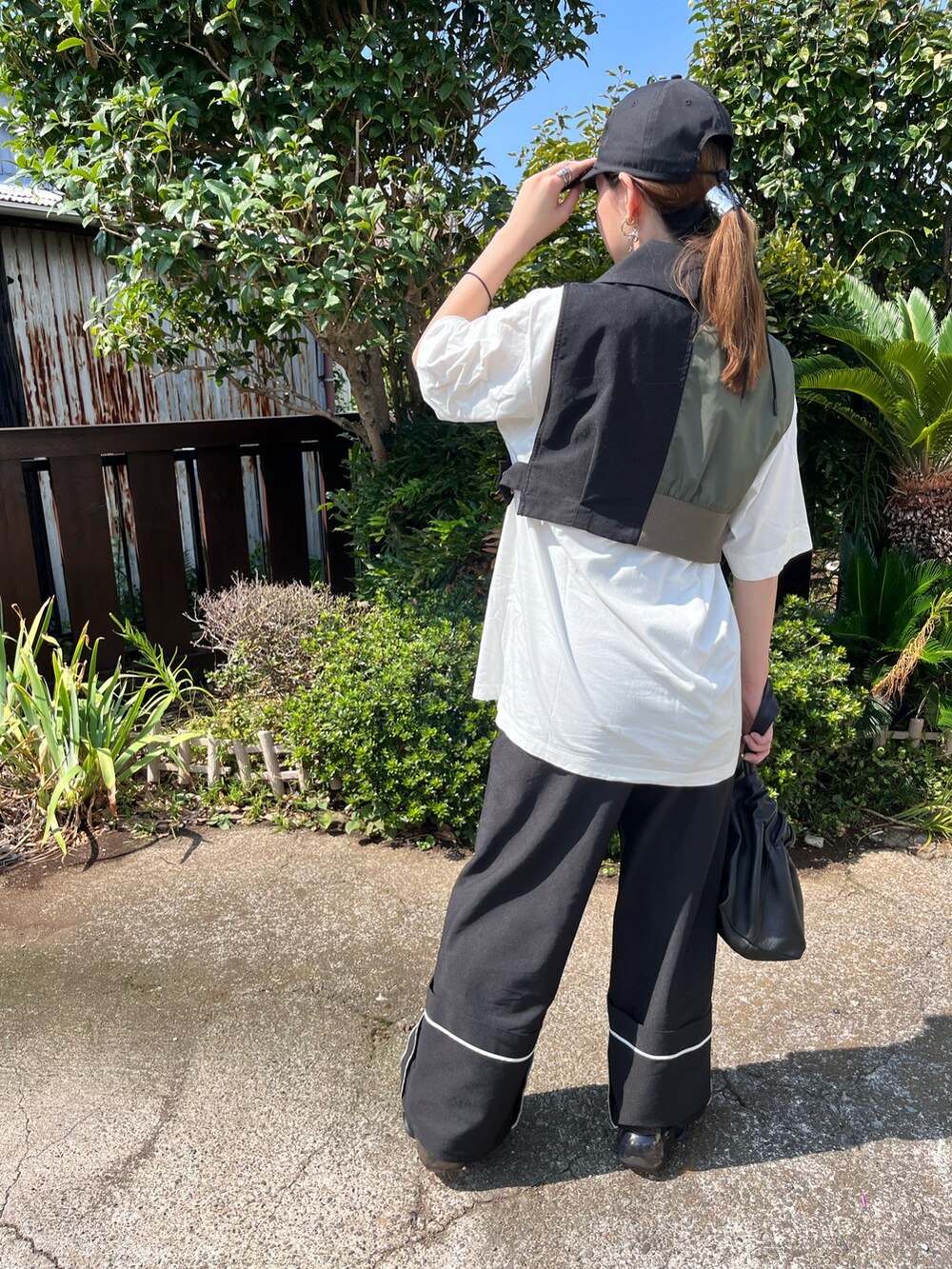 ブラック系のベスト、ホワイト系のTシャツ/カットソー、ブラック系のハンドバッグを着用したレディースの秋コーディネートの2枚目の写真