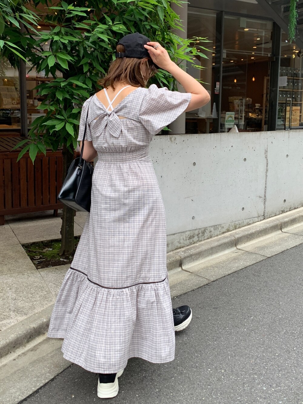 ホワイト系のワンピース、ブラック系のショルダーバッグ、ブラック系のスニーカーを着用したレディースの夏コーディネートの2枚目の写真