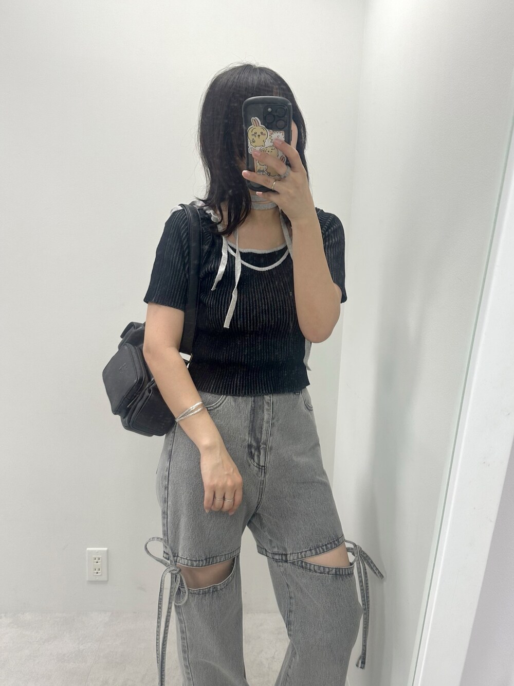 ブラック系のニット/セーター、ブラック系のショルダーバッグ、グレー系のデニムパンツを着用したレディースの夏コーディネートの2枚目の写真