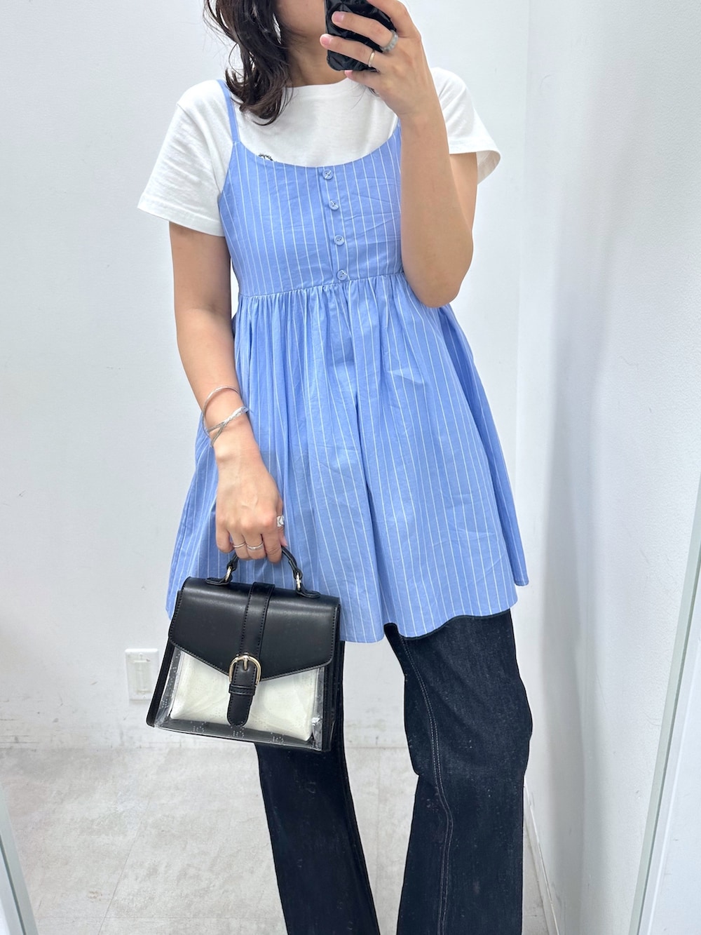 ブルー系のチュニック、ブルー系のデニムパンツ、ブラック系のショルダーバッグを着用したレディースの春コーディネートの2枚目の写真