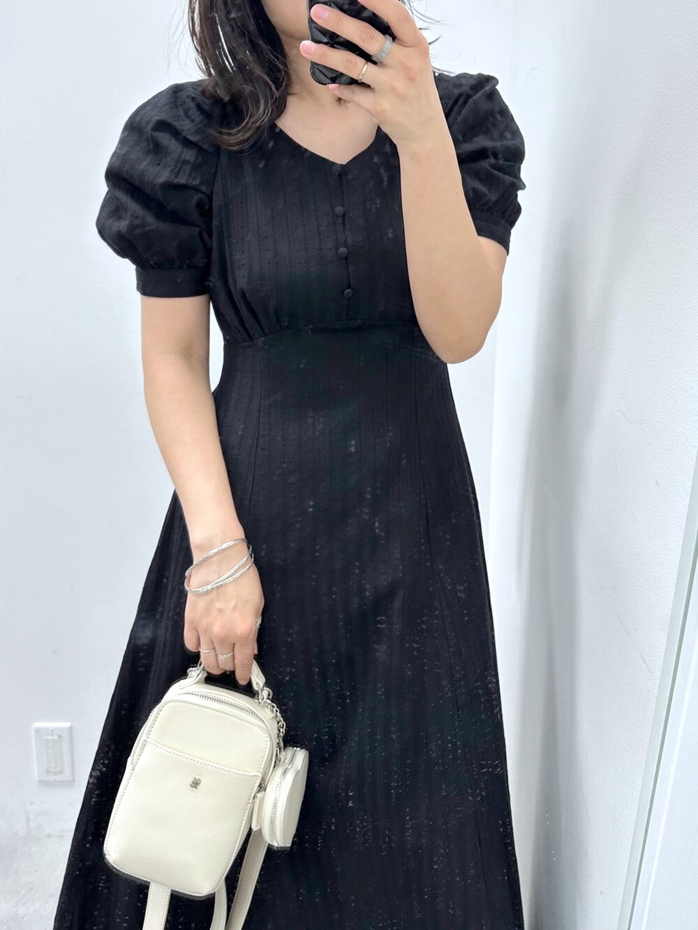 ブラック系のワンピース、ホワイト系のショルダーバッグ、ホワイト系のスニーカーを着用したレディースの春コーディネートの2枚目の写真