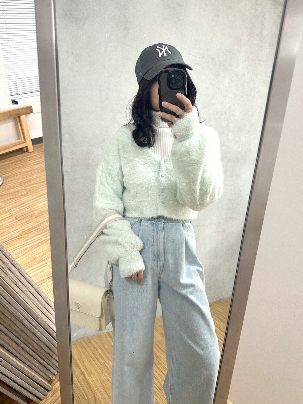 ブルー系のデニムパンツ、グリーン系のカーディガン/ボレロ、ホワイト系のニット/セーターを着用したレディースの冬コーディネートの2枚目の写真