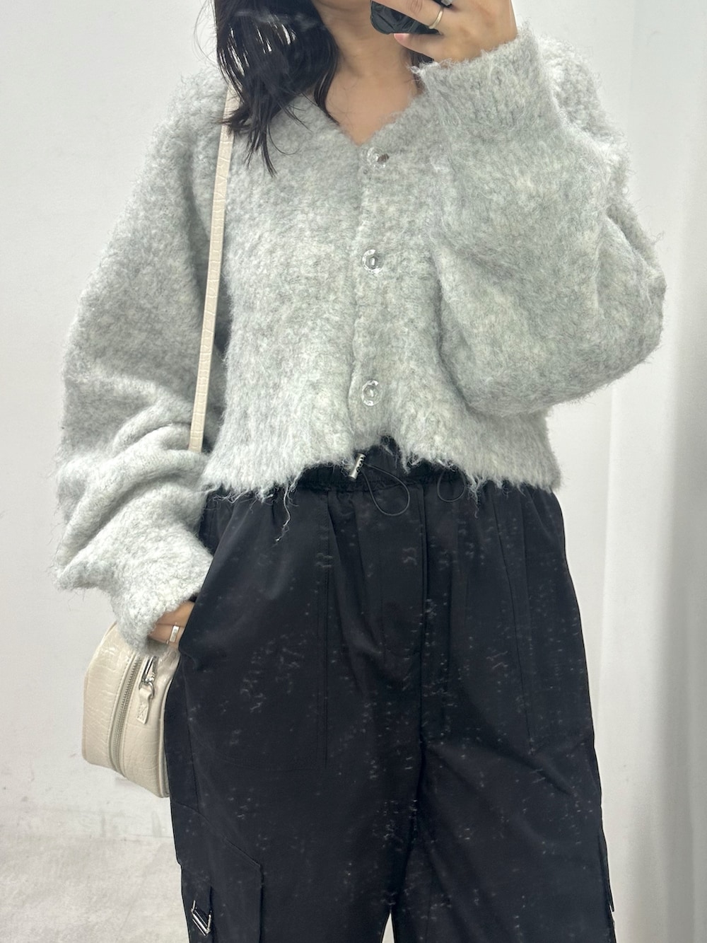 ブラック系のカーゴパンツ、ベージュ系のカーディガン/ボレロ、ホワイト系のショルダーバッグを着用したレディースの秋コーディネートの2枚目の写真