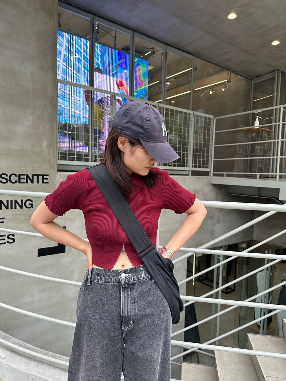 ブラック系のデニムパンツ、レッド系のニット/セーター、ホワイト系のスニーカーを着用したレディースの夏コーディネートの2枚目の写真