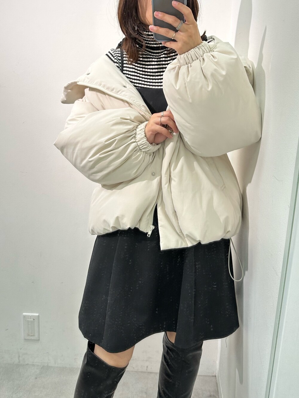 ブラック系のワンピース、ホワイト系のダウンジャケット/コート、ブラック系のニット/セーターを着用したレディースの冬コーディネートの2枚目の写真