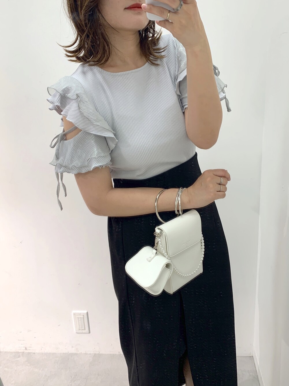 ブラック系のスカート、グレー系のTシャツ/カットソー、ホワイト系のショルダーバッグを着用したレディースの春コーディネートの2枚目の写真