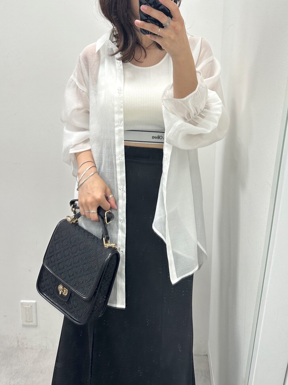 ブラック系のスカート、ホワイト系のタンクトップ、ホワイト系のシャツ/ブラウスを着用したレディースの春コーディネートの2枚目の写真