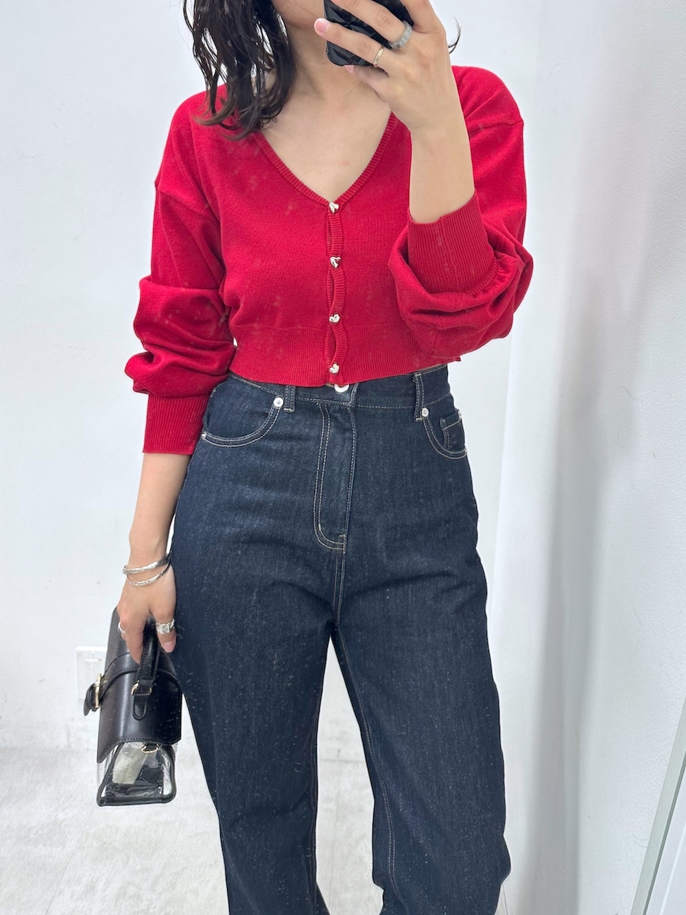 レッド系のカーディガン/ボレロ、ブルー系のデニムパンツ、ブラック系のショルダーバッグを着用したレディースの春コーディネートの2枚目の写真