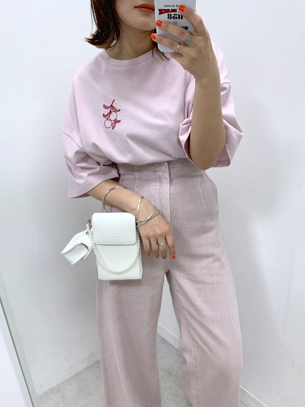 パープル系のデニムパンツ、ピンク系のTシャツ/カットソー、ホワイト系のサンダルを着用したレディースの春コーディネートの2枚目の写真