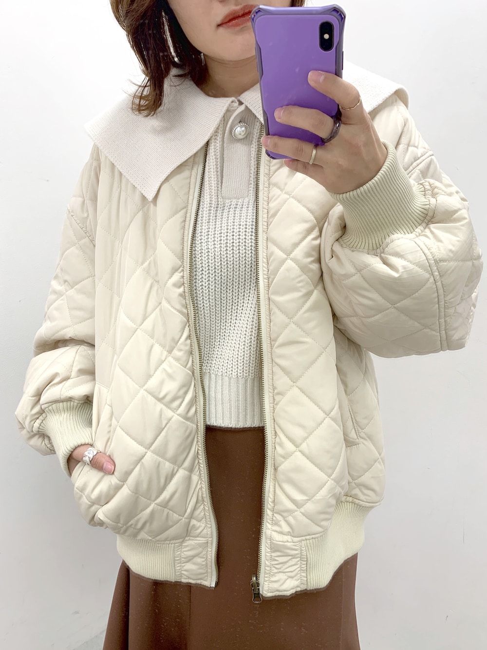 ホワイト系のブルゾン、ホワイト系のニット/セーター、ブラウン系のスカートを着用したレディースの冬コーディネートの2枚目の写真