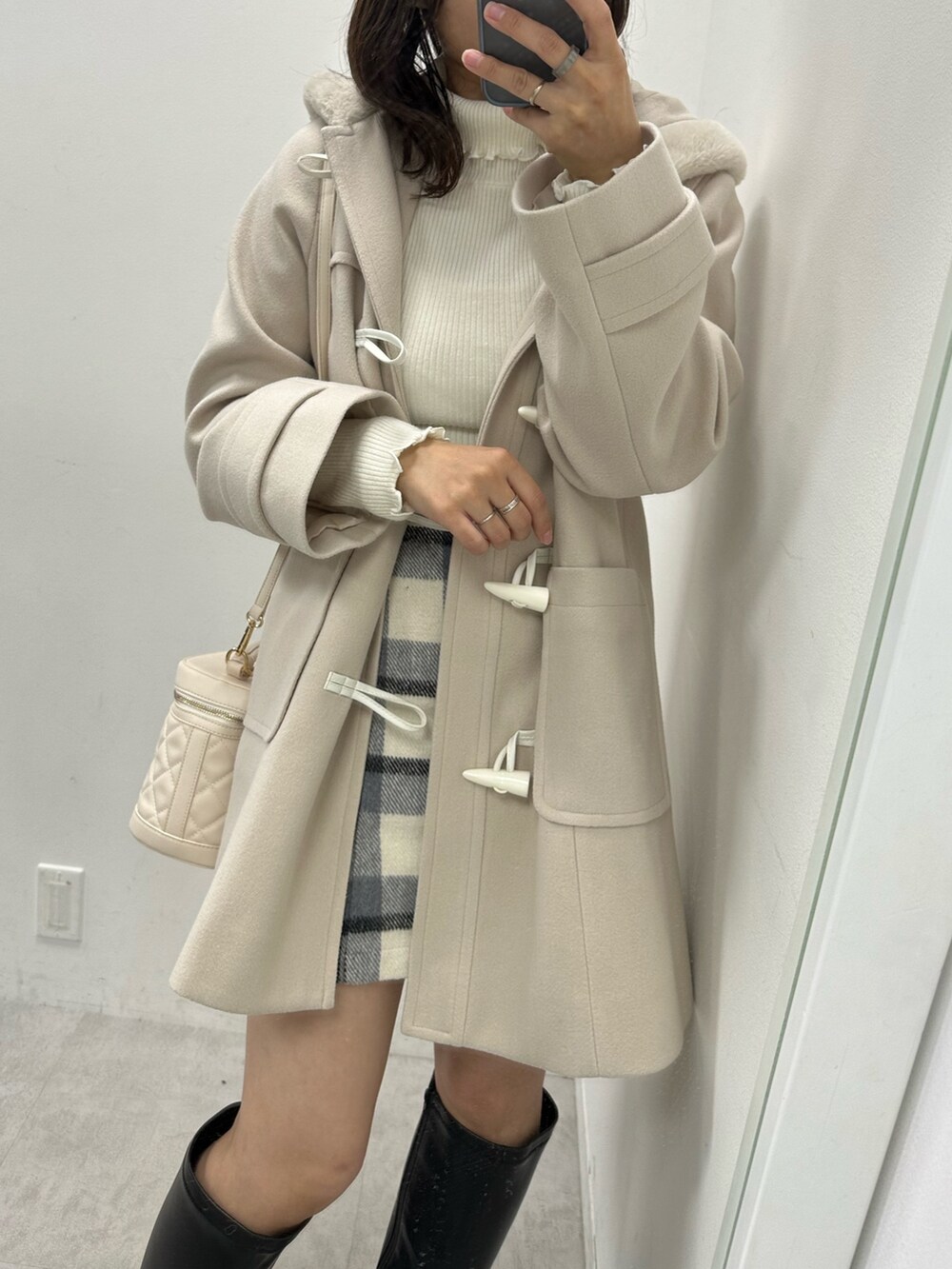 グレー系のスカート、ホワイト系のニット/セーター、ホワイト系のダッフルコートを着用したレディースの秋コーディネートの2枚目の写真