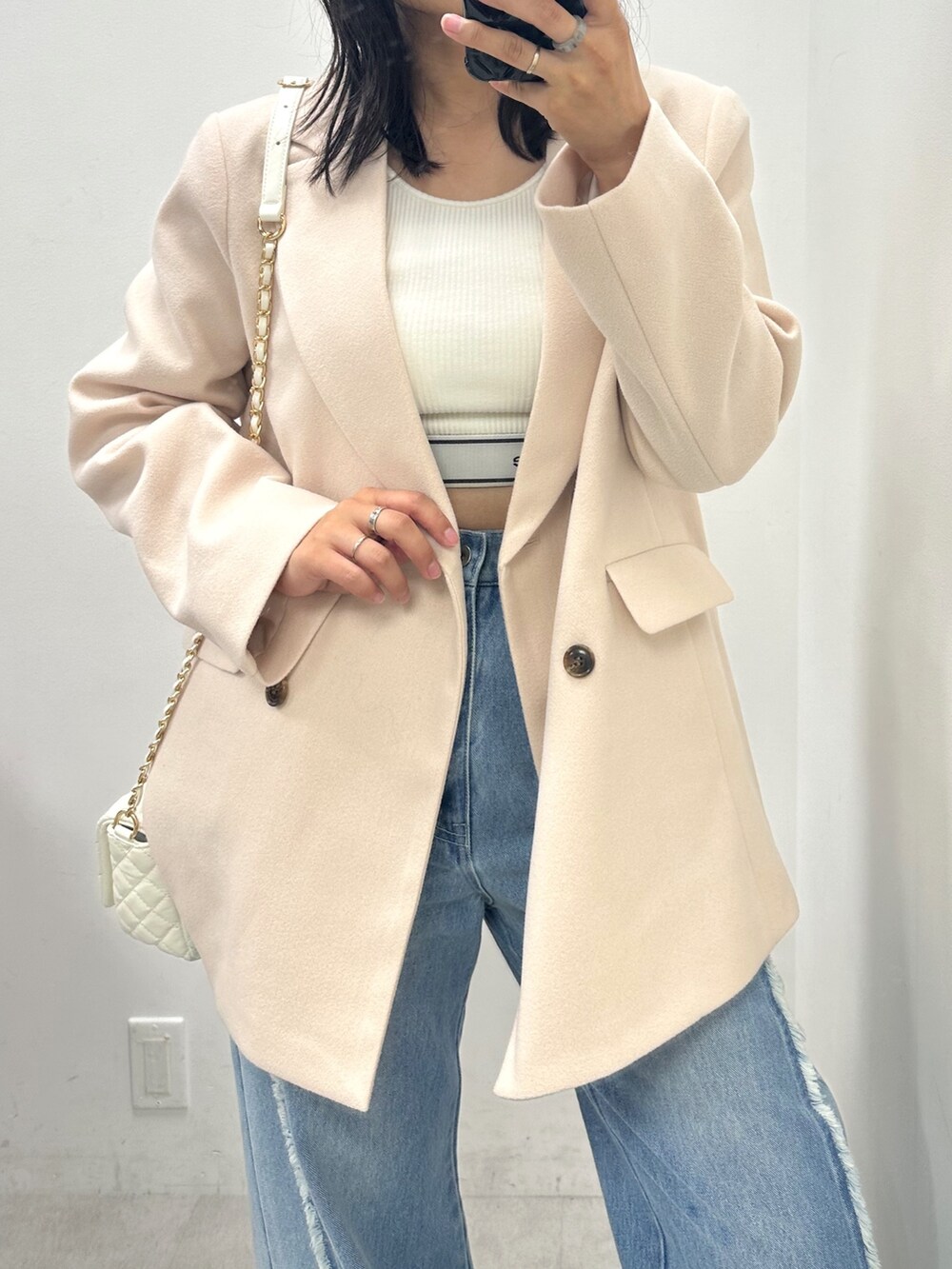 ブルー系のデニムパンツ、ホワイト系のテーラードジャケット、ホワイト系のタンクトップを着用したレディースの秋コーディネートの2枚目の写真