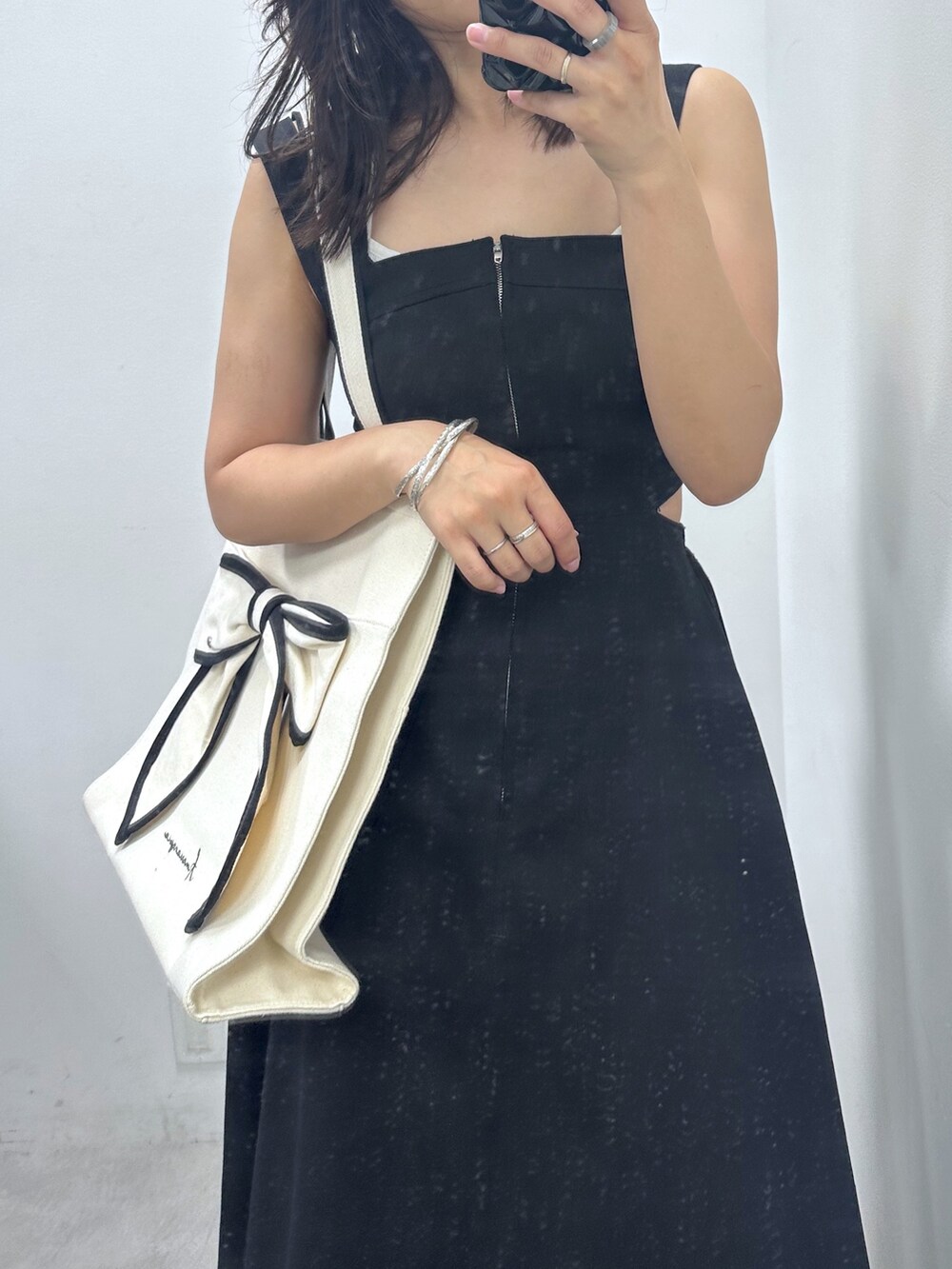 ブラック系のジャンパースカート、ブラック系のトートバッグ、ブラック系のスニーカーを着用したレディースの夏コーディネートの2枚目の写真