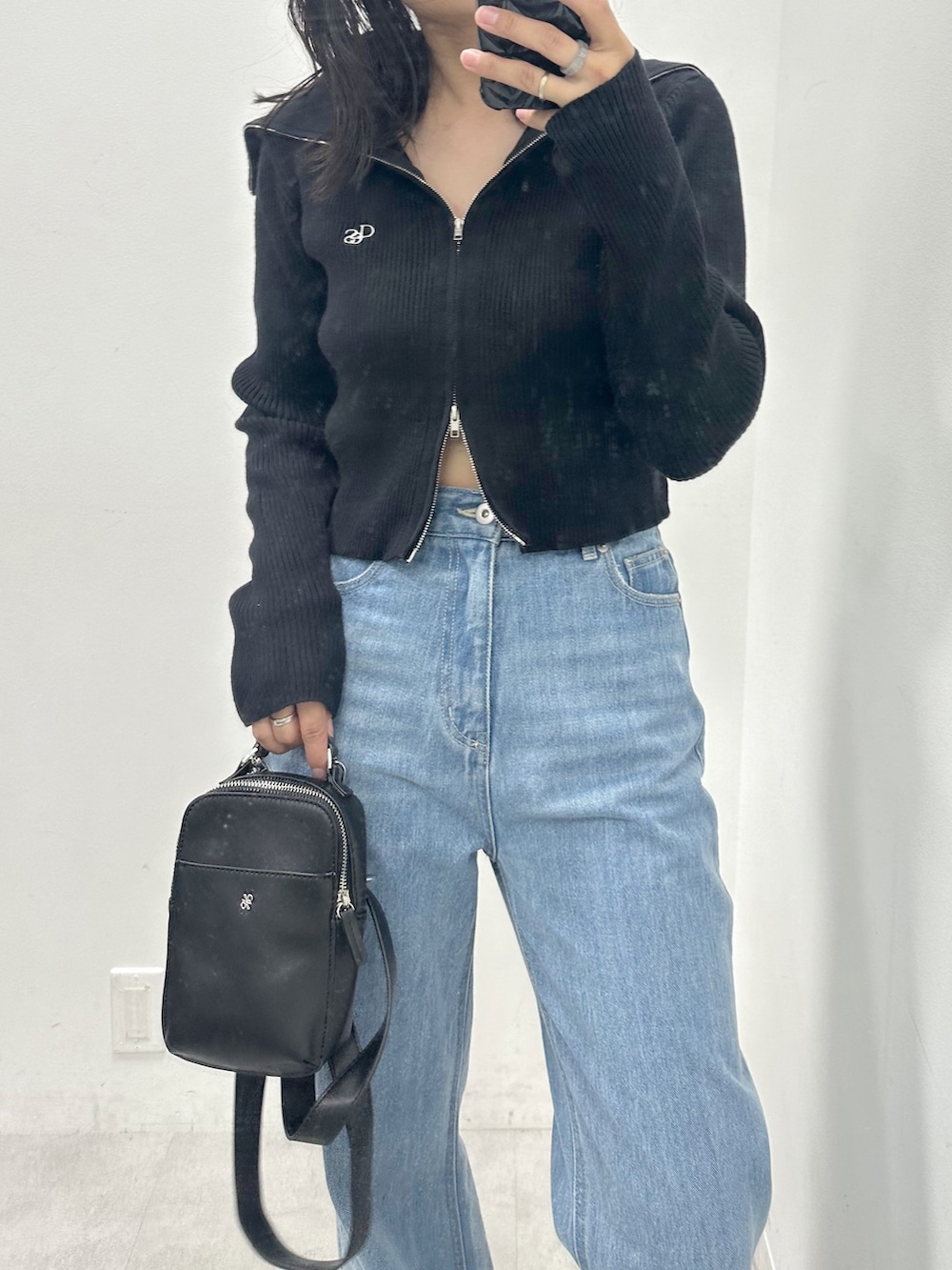 ブルー系のデニムパンツ、ブラック系のニット/セーター、ブラック系のショルダーバッグを着用したレディースの夏コーディネートの2枚目の写真