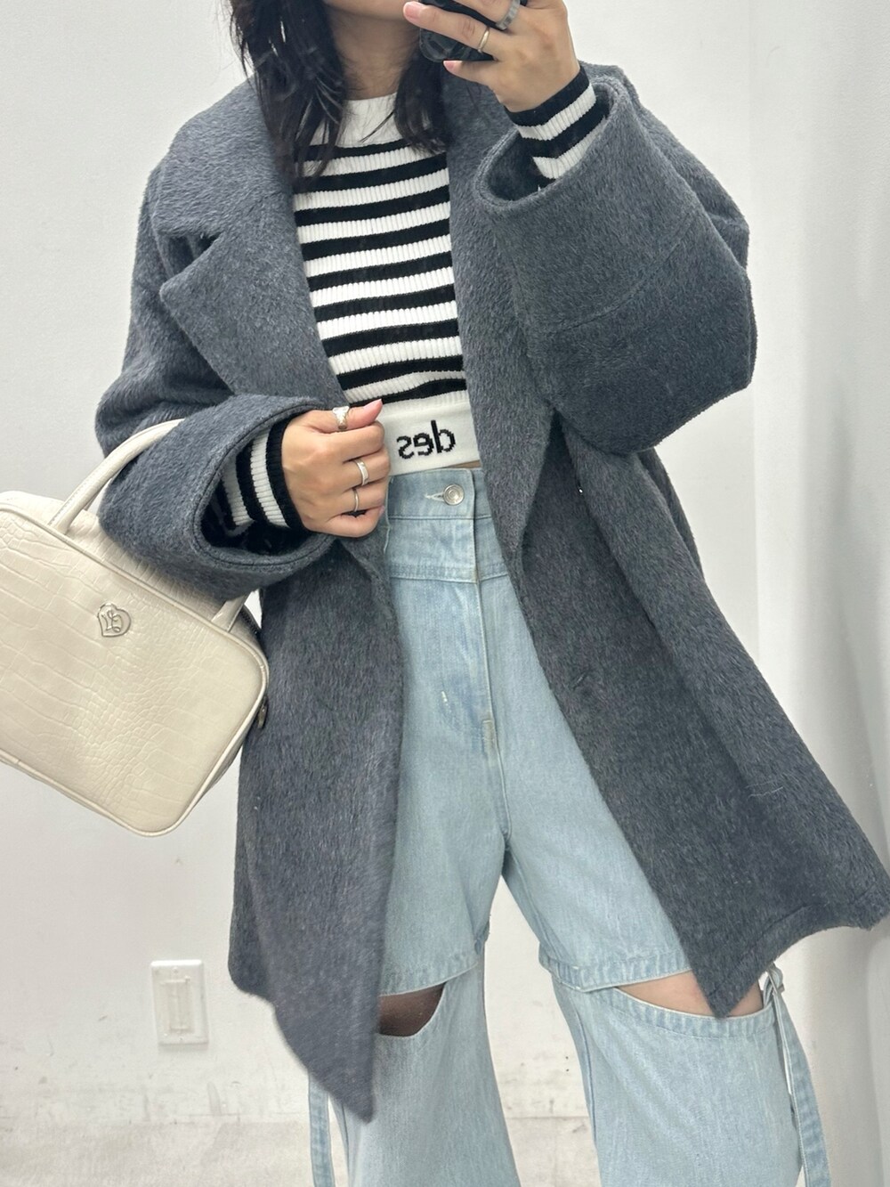 ブルー系のデニムパンツ、ホワイト系のニット/セーター、グレー系のテーラードジャケットを着用したレディースの秋コーディネートの2枚目の写真