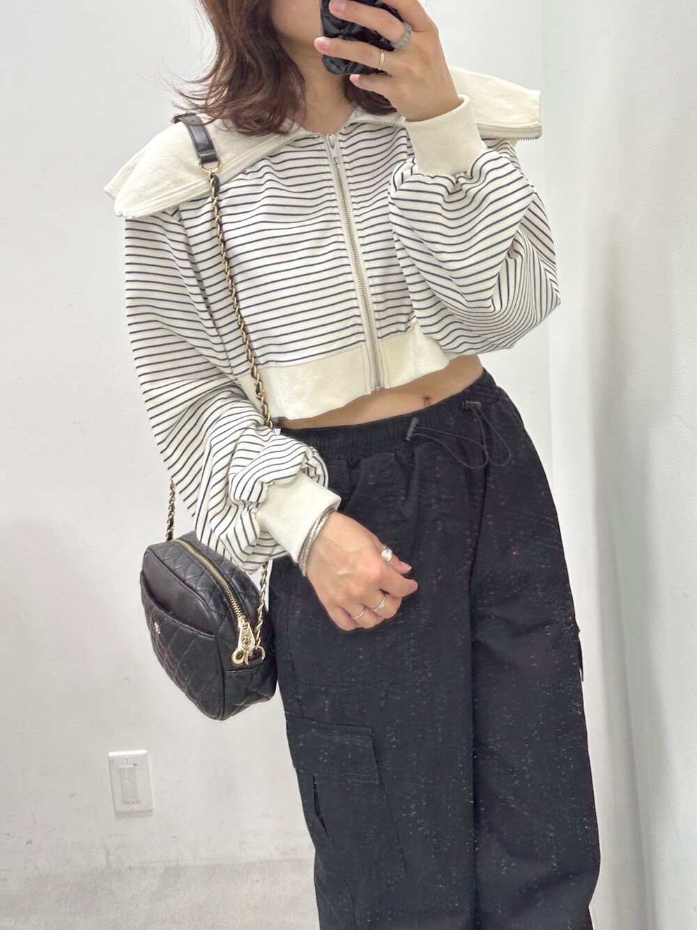 ブラック系のカーゴパンツ、ホワイト系のパーカー、ブラック系のショルダーバッグを着用したレディースの春コーディネートの2枚目の写真