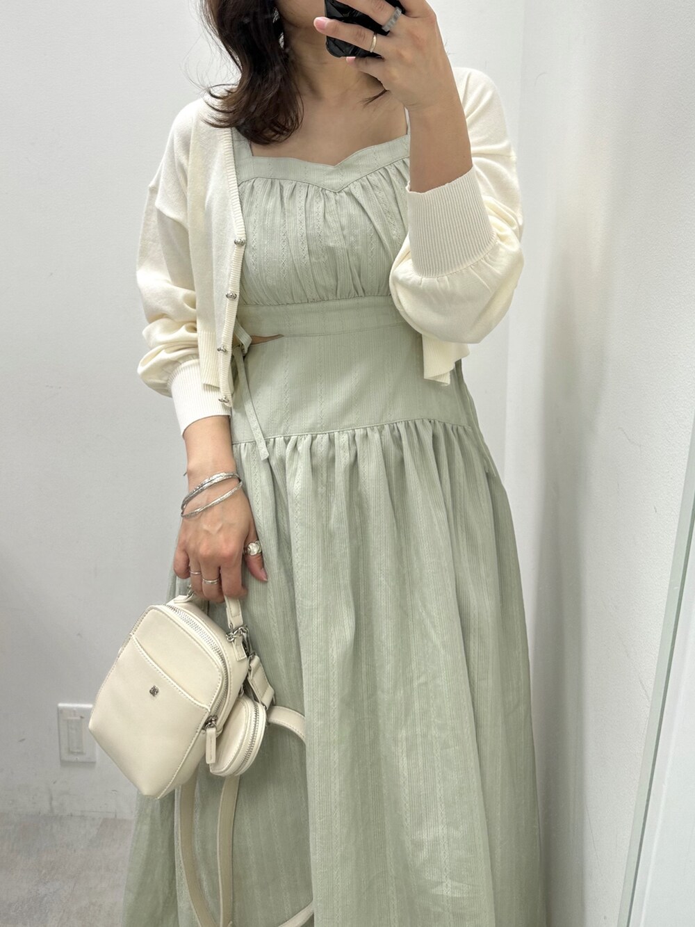 ホワイト系のショルダーバッグ、グリーン系のワンピース、ホワイト系のカーディガン/ボレロを着用したレディースの春コーディネートの2枚目の写真