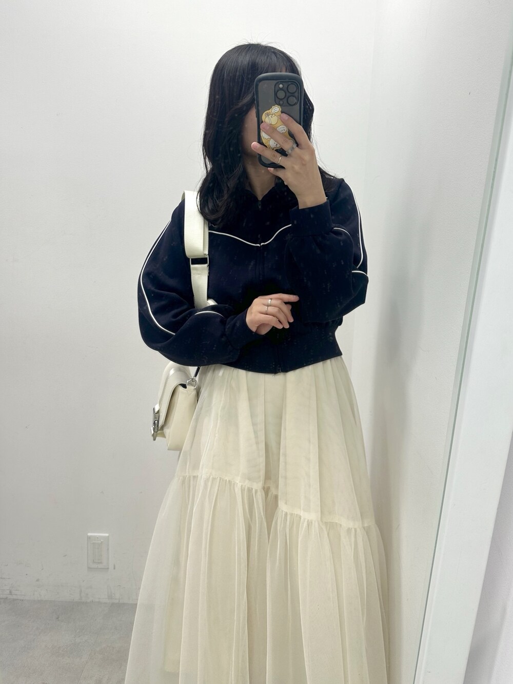 ホワイト系のスカート、ブルー系のブルゾン、ホワイト系のショルダーバッグを着用したレディースの冬コーディネートの2枚目の写真