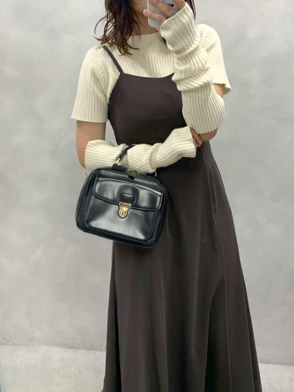 ブラウン系のワンピース、ホワイト系のニット/セーター、ブラック系のショルダーバッグを着用したレディースの秋コーディネートの2枚目の写真