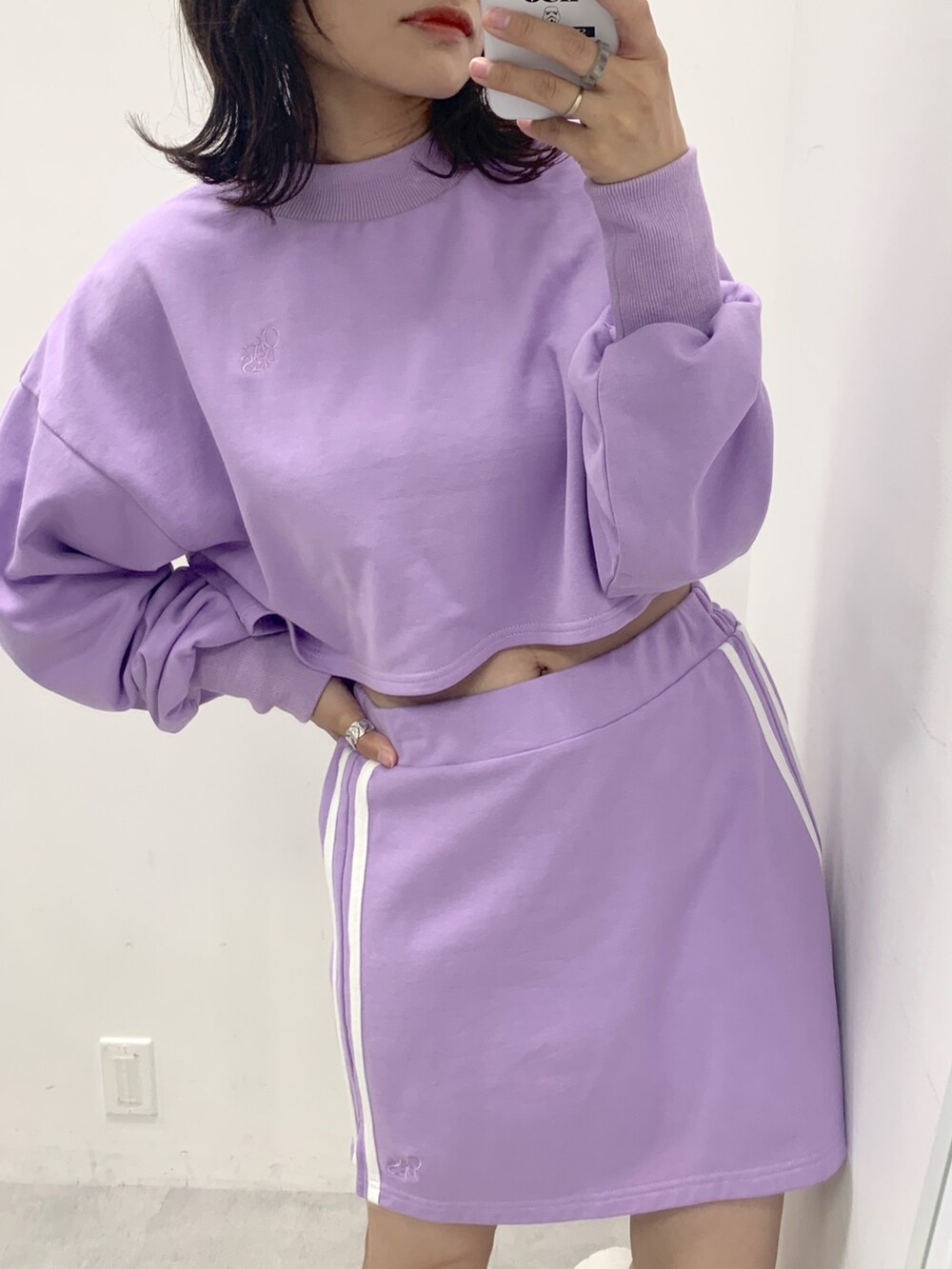 パープル系のスカート、パープル系のスウェット、ホワイト系のスニーカーを着用したレディースの夏コーディネートの2枚目の写真