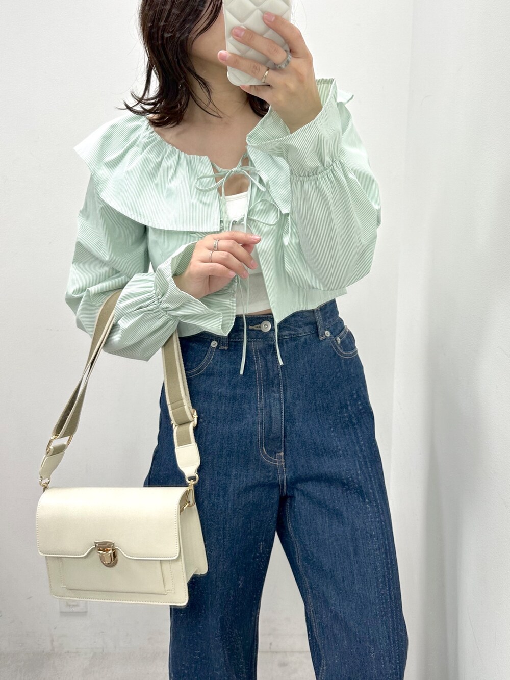 ブルー系のデニムパンツ、グリーン系のシャツ/ブラウス、ホワイト系のショルダーバッグを着用したレディースの冬コーディネートの2枚目の写真