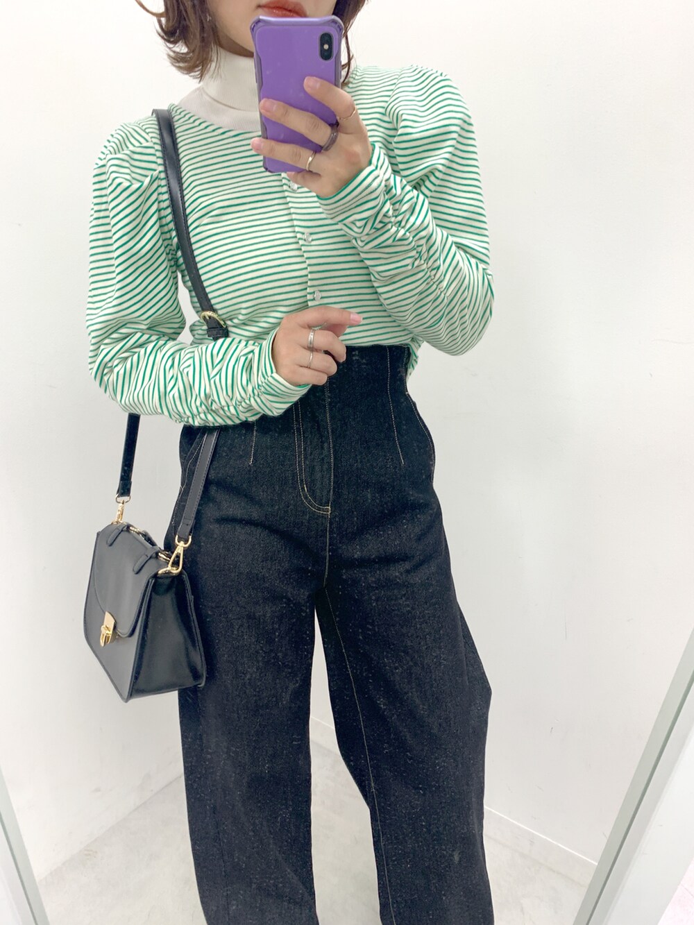 ブラック系のデニムパンツ、グリーン系のカーディガン/ボレロ、ブラック系のショルダーバッグを着用したレディースの冬コーディネートの2枚目の写真