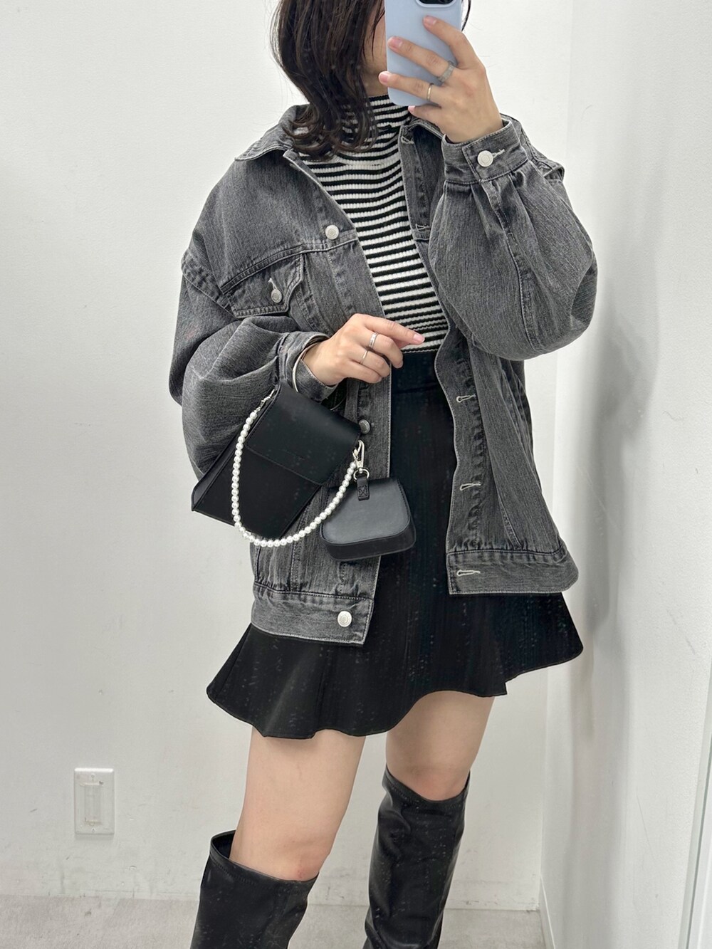 ブラック系のニット/セーター、ブラック系のデニムジャケット、ブラック系のショルダーバッグを着用したレディースの冬コーディネートの2枚目の写真