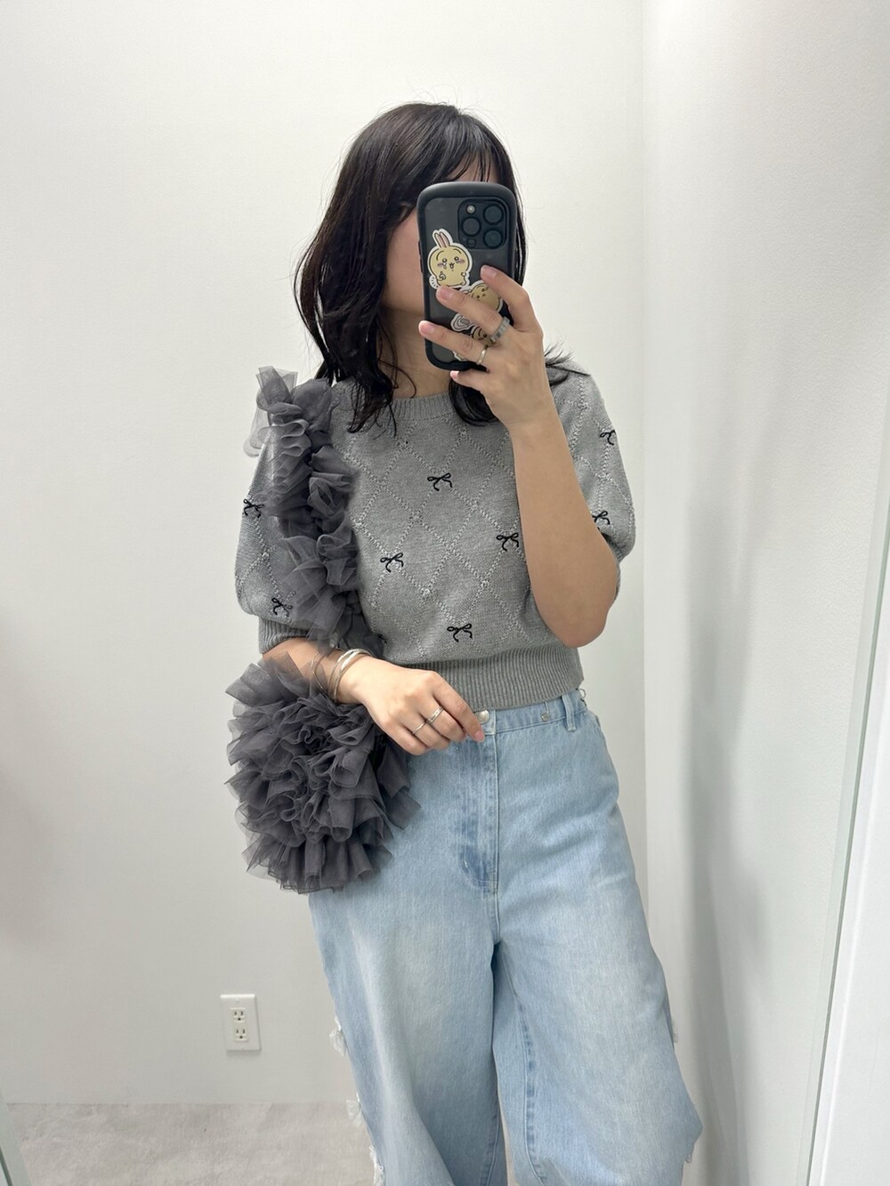 ブルー系のデニムパンツ、グレー系のニット/セーター、グレー系のショルダーバッグを着用したレディースの春コーディネートの2枚目の写真