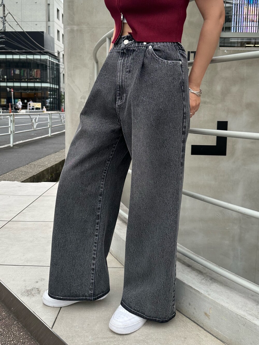 ブラック系のデニムパンツ、レッド系のニット/セーター、ホワイト系のスニーカーを着用したレディースの夏コーディネートの3枚目の写真