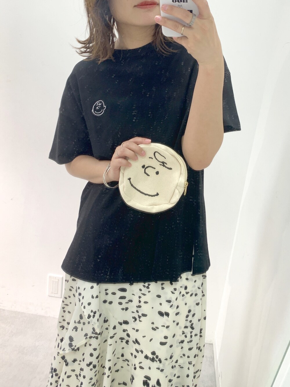 ホワイト系のスカート、ブラック系のTシャツ/カットソー、ブラック系のサンダルを着用したレディースの夏コーディネートの2枚目の写真