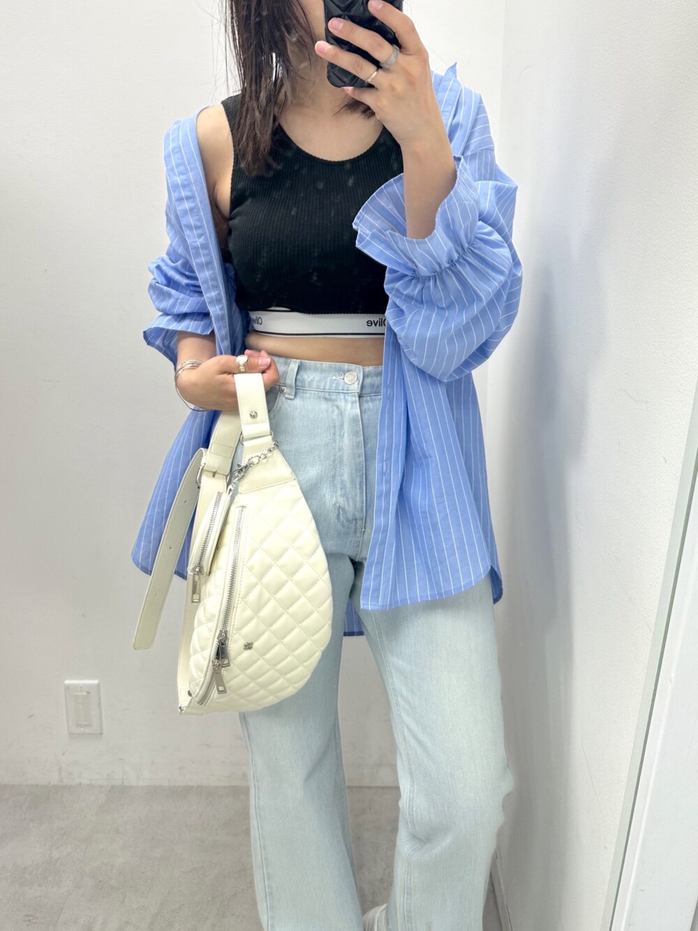 ホワイト系のボディバッグ/ウエストポーチ、ブラック系のタンクトップ、ブルー系のデニムパンツを着用したレディースの春コーディネートの2枚目の写真