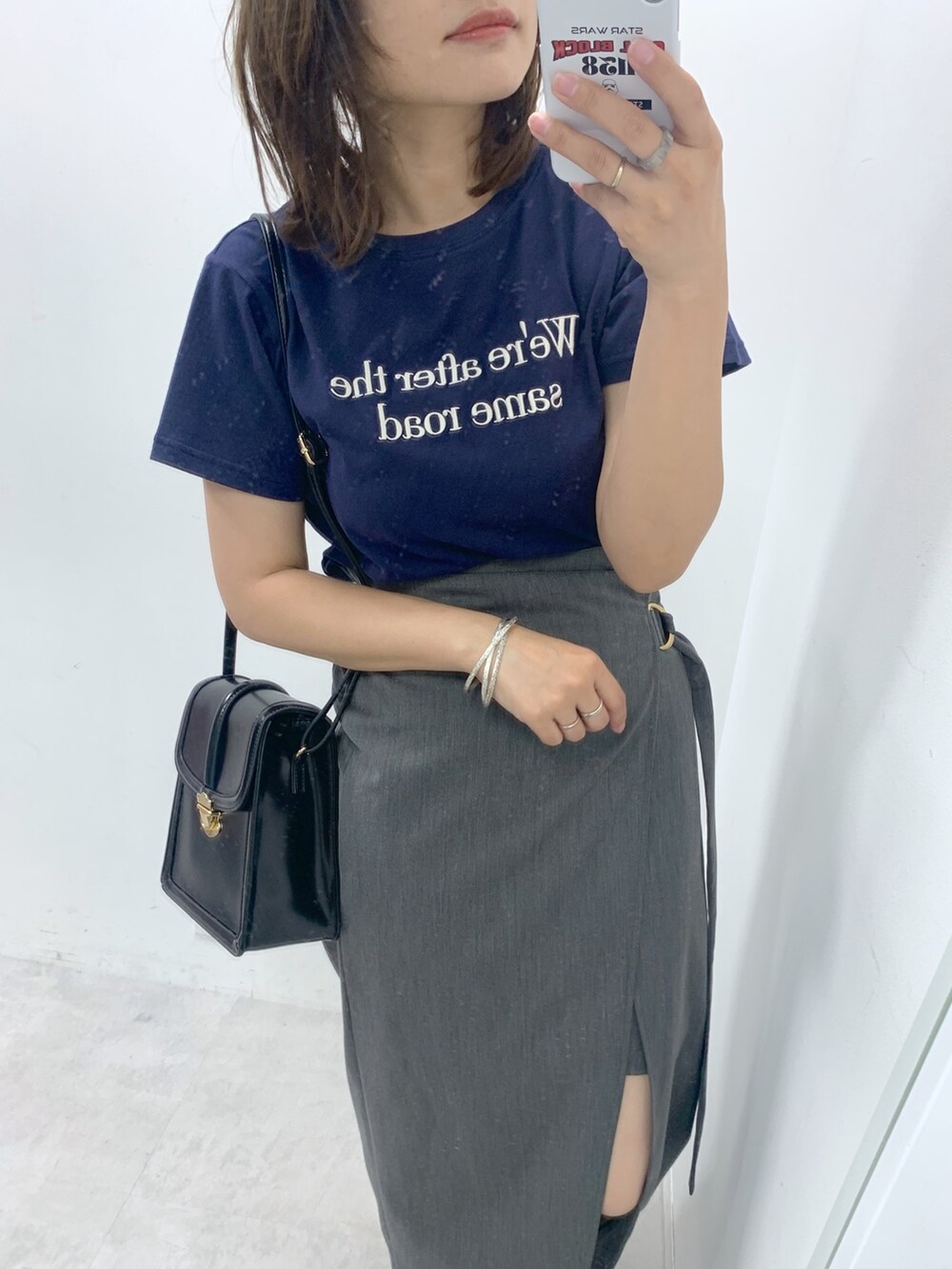 グレー系のスカート、ブルー系のTシャツ/カットソー、ブラック系のショルダーバッグを着用したレディースの夏コーディネートの2枚目の写真