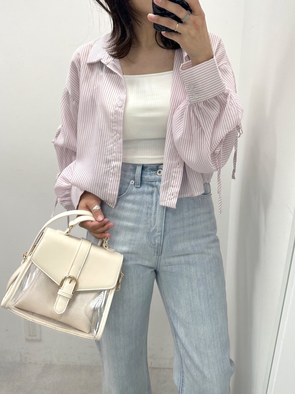 ブルー系のデニムパンツ、パープル系のシャツ/ブラウス、ホワイト系のショルダーバッグを着用したレディースの春コーディネートの2枚目の写真