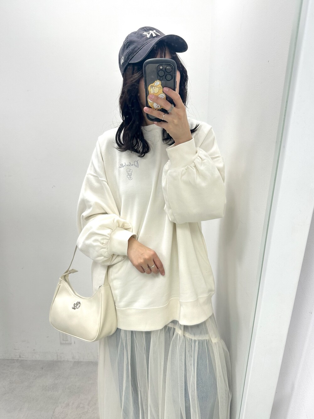ホワイト系のスウェット、ホワイト系のスカート、ホワイト系のショルダーバッグを着用したレディースの冬コーディネートの2枚目の写真