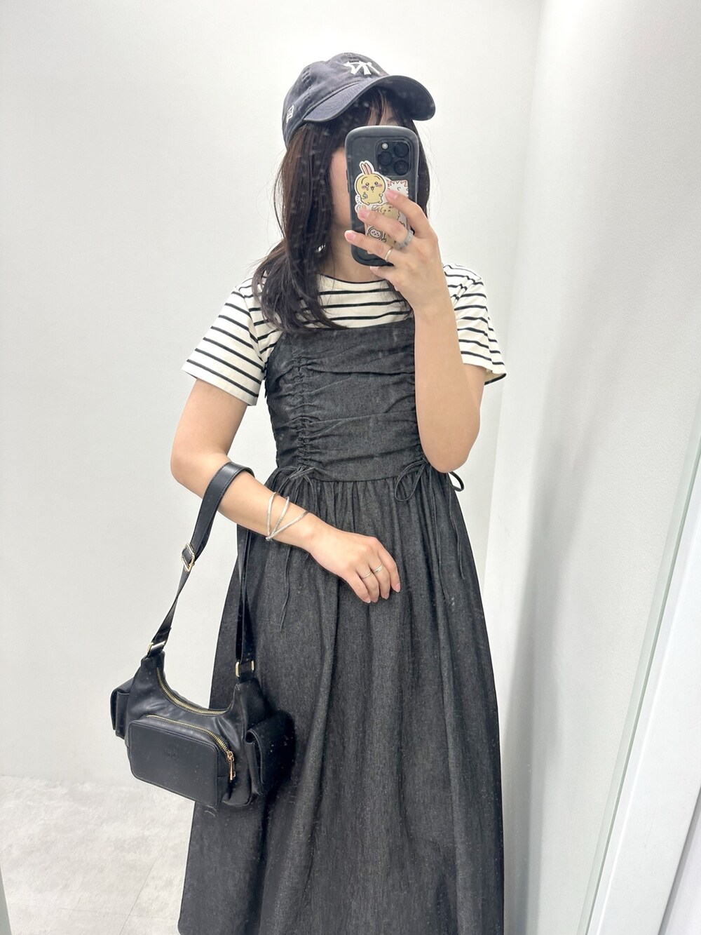 ブラック系のワンピース、ブラック系のTシャツ/カットソー、ブラック系のショルダーバッグを着用したレディースの春コーディネートの2枚目の写真