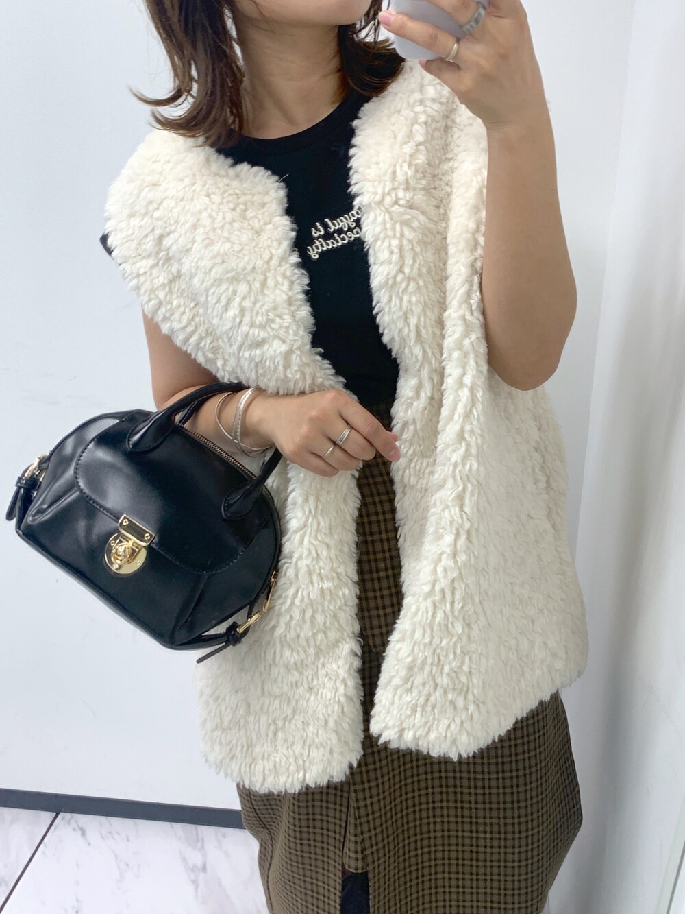 ホワイト系のベスト、ブラック系のTシャツ/カットソー、ブラウン系のスカートを着用したレディースの夏コーディネートの2枚目の写真