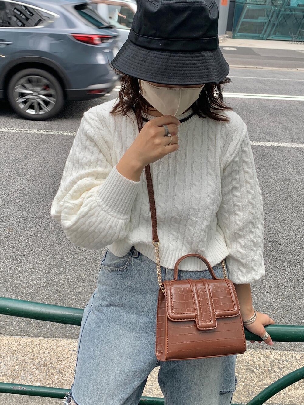 ブルー系のデニムパンツ、ホワイト系のニット/セーター、ブラウン系のショルダーバッグを着用したレディースの夏コーディネートの2枚目の写真