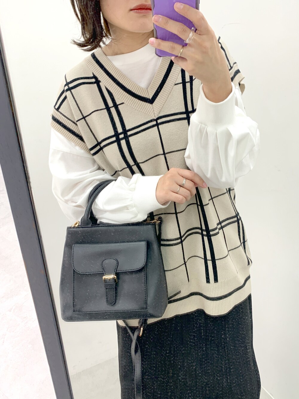 ブラック系のショルダーバッグ、ベージュ系のベスト、ブラック系のスカートを着用したレディースの冬コーディネートの2枚目の写真