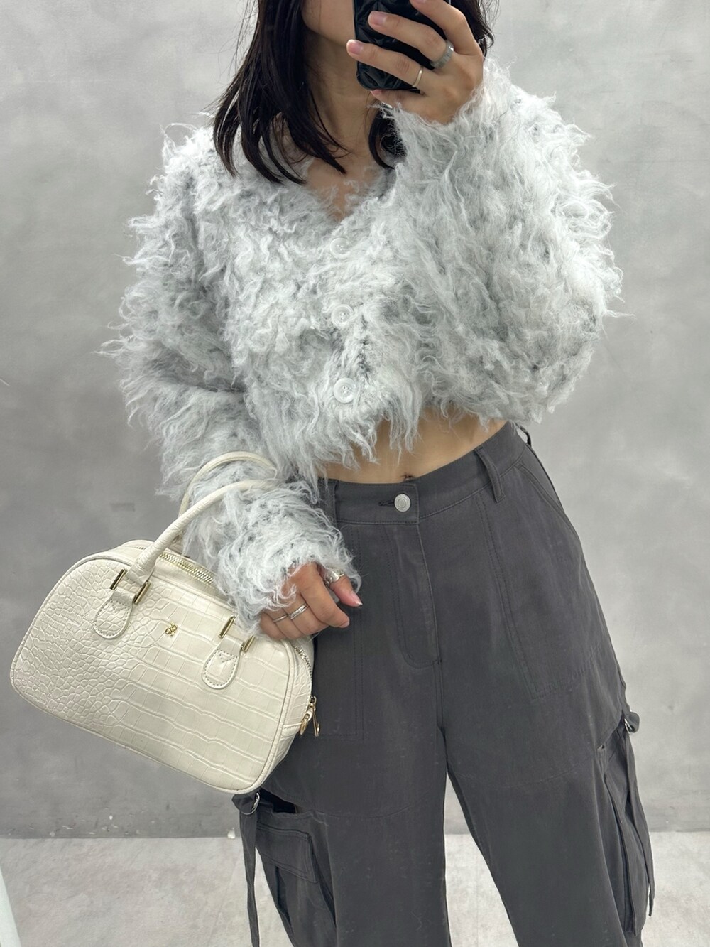 グレー系のカーゴパンツ、ベージュ系のカーディガン/ボレロ、ホワイト系のショルダーバッグを着用したレディースの秋コーディネートの2枚目の写真