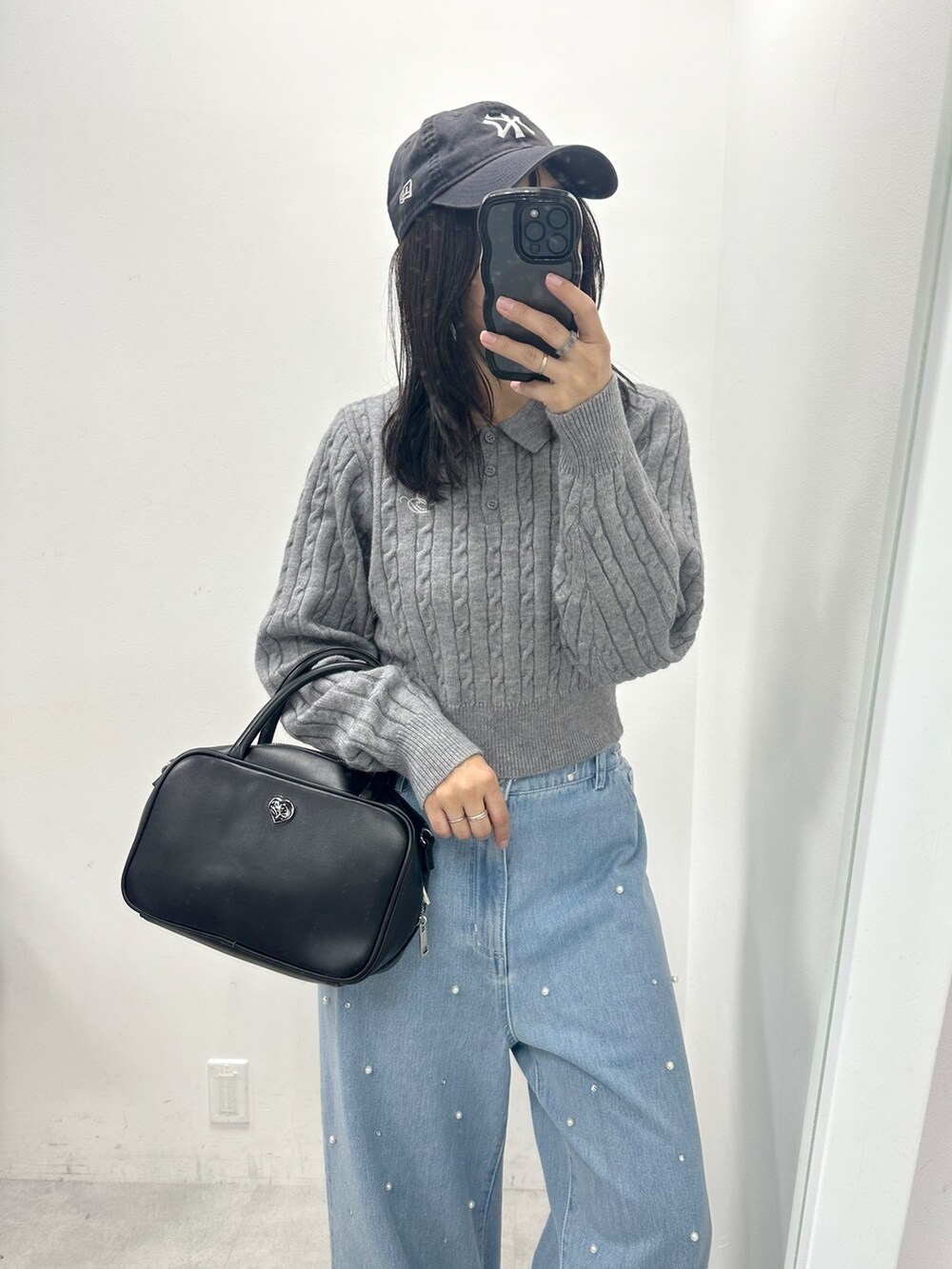 グレー系のニット/セーター、ブラック系のショルダーバッグ、ブルー系のデニムパンツを着用したレディースの冬コーディネートの2枚目の写真