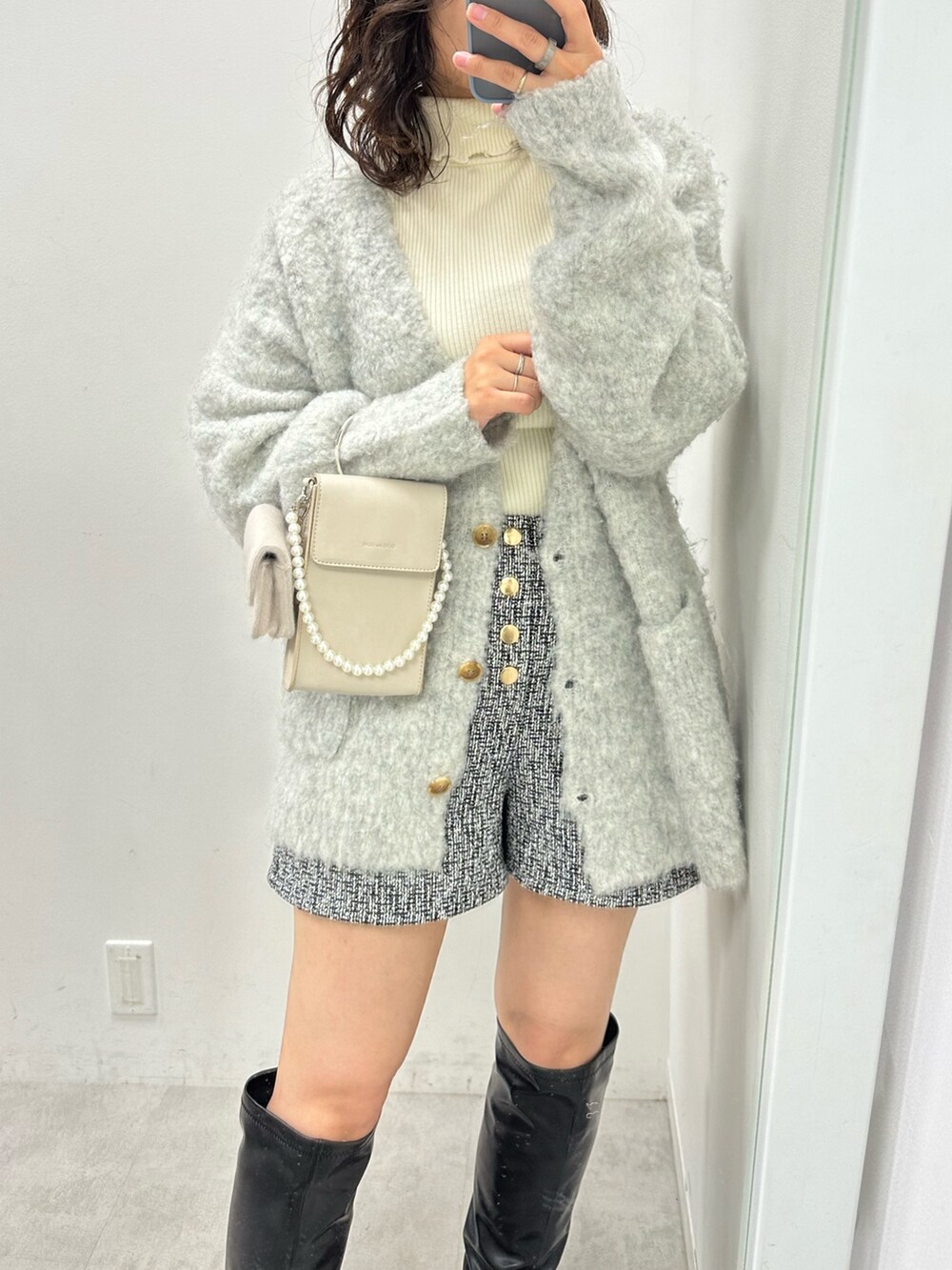 グレー系のカーディガン/ボレロ、ホワイト系のニット/セーター、ベージュ系のショルダーバッグを着用したレディースの秋コーディネートの2枚目の写真