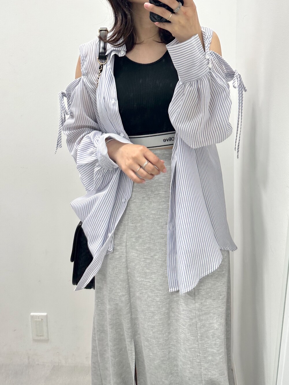 グレー系のスカート、ホワイト系のスニーカー、ブラック系のタンクトップを着用したレディースの夏コーディネートの2枚目の写真