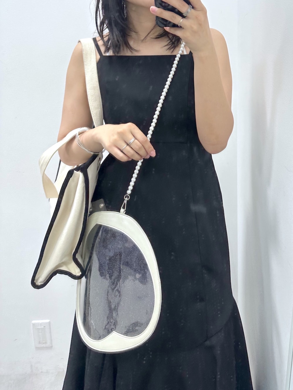 ブラック系のワンピース、ブラック系のトートバッグ、ホワイト系のスニーカーを着用したレディースの夏コーディネートの2枚目の写真