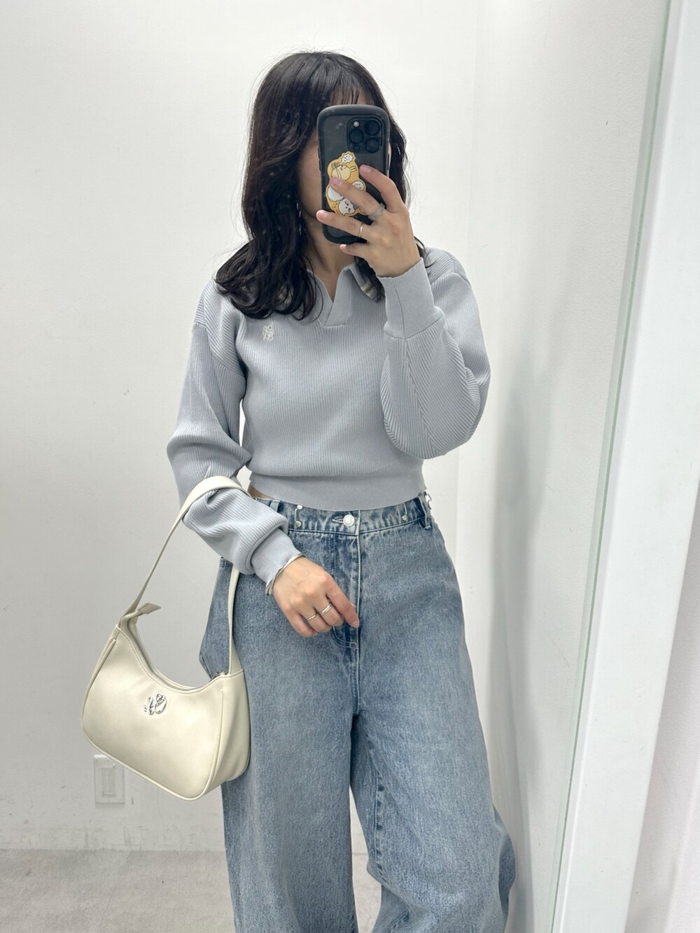 ブルー系のデニムパンツ、ブルー系のニット/セーター、ホワイト系のショルダーバッグを着用したレディースの春コーディネートの2枚目の写真