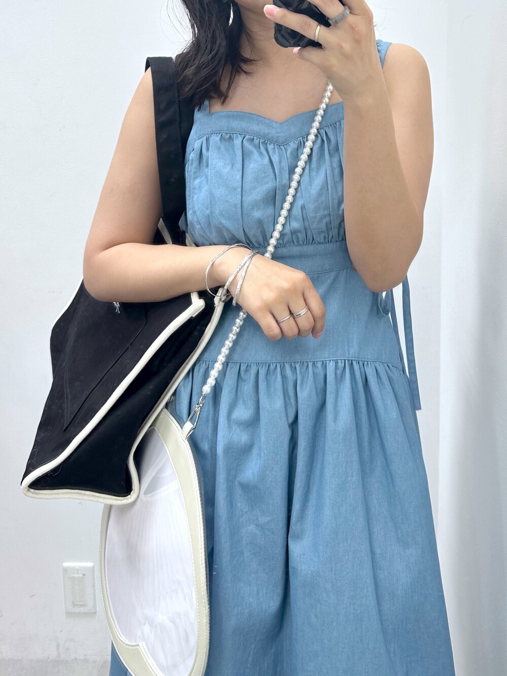 ブラック系のトートバッグ、ブルー系のワンピース、ホワイト系のスニーカーを着用したレディースの夏コーディネートの2枚目の写真